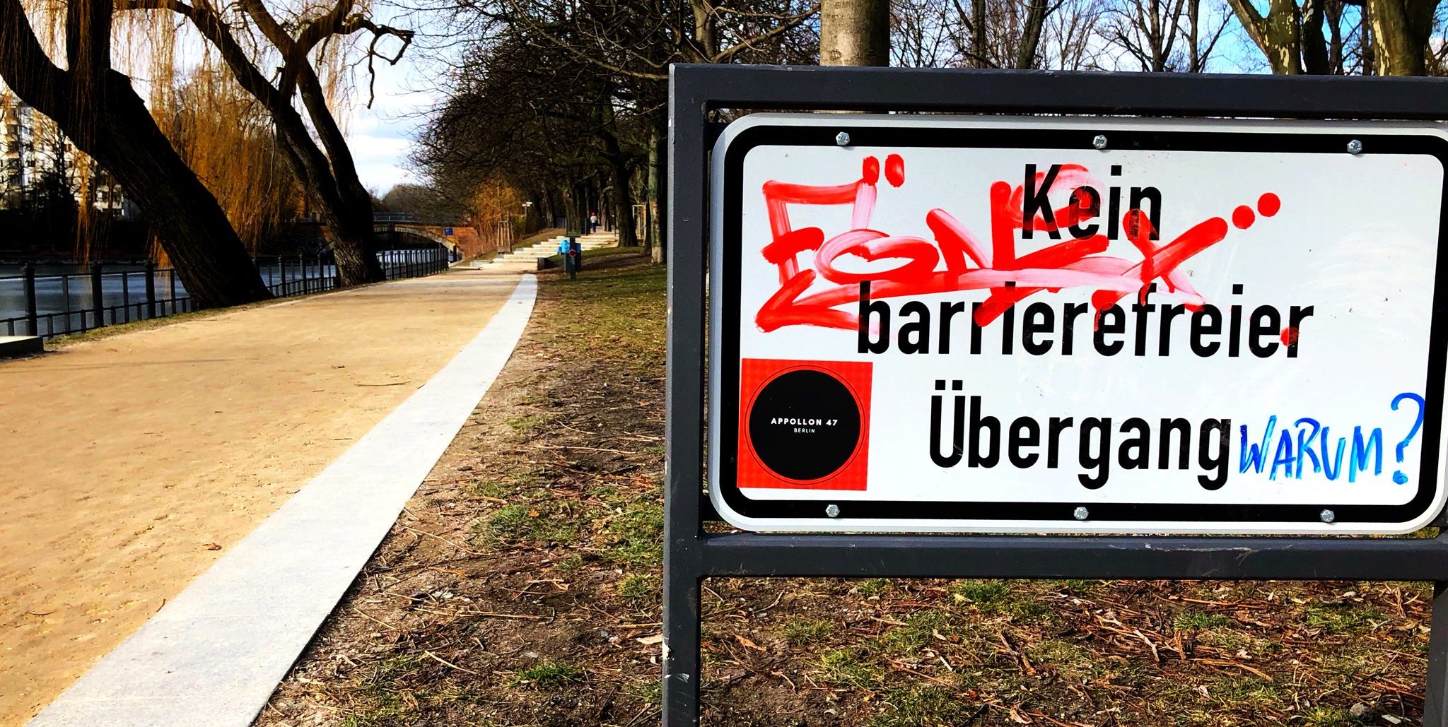 Schild mit der Aufschrift: "Kein Barrierefreier Übergang. Warum?"